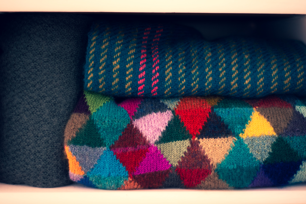 Colorful Hand Knitted Wool Sweaters Folded in a Wardrobe