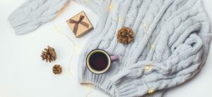cosy jumper with a cup of coffee pine cones and present around it