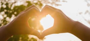hands in shape of love heart and sunshine