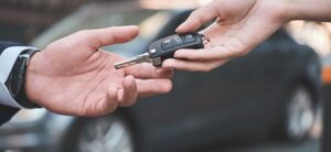 person handing keys over at a car dealership