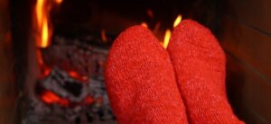 person wearing red socks warming their feet by a fire