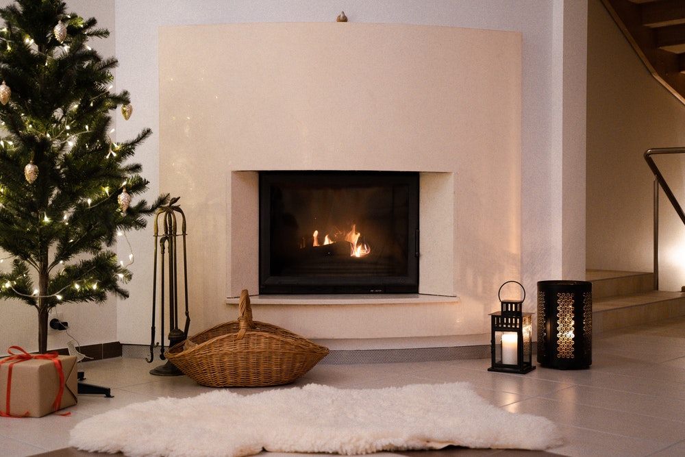 Christmas tree stood beside a white fireplace