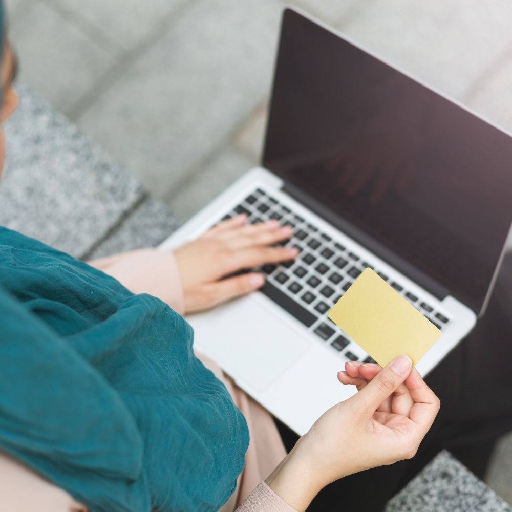 women sat on her laptop with a credit card in hand
