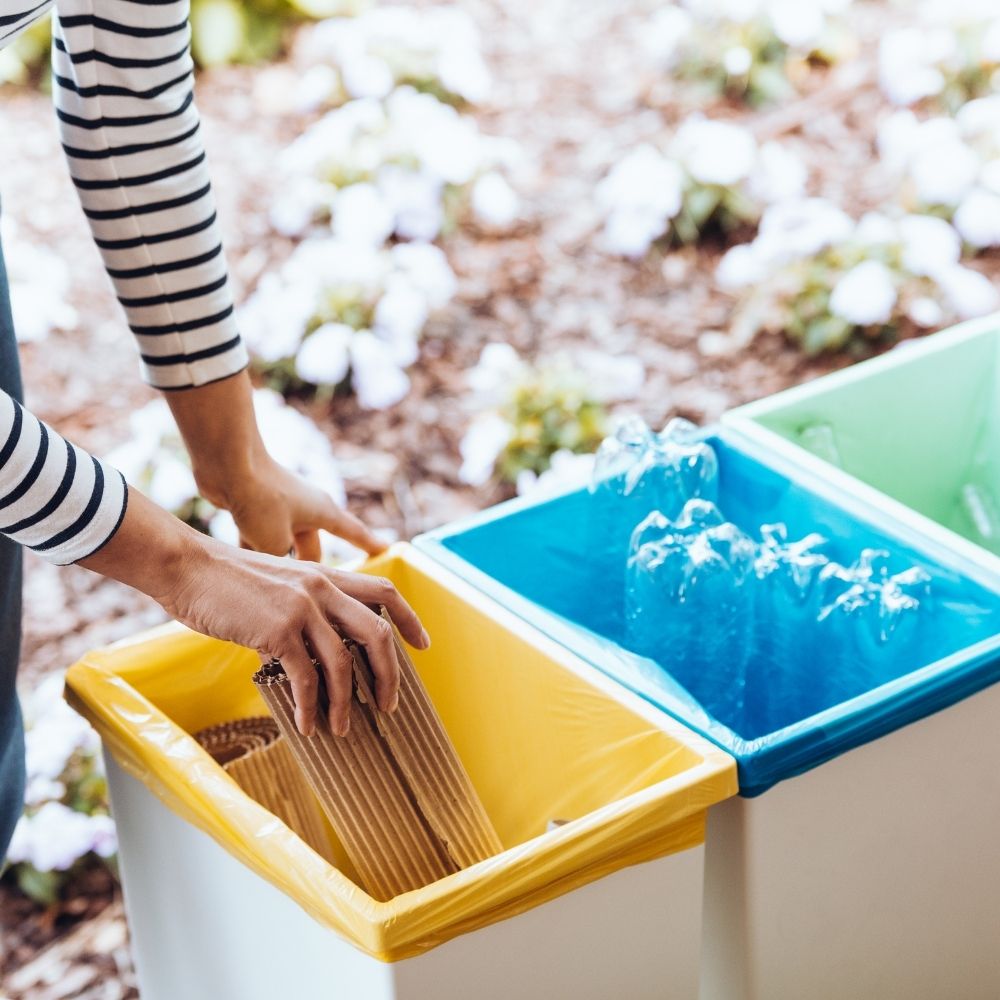 person putting paper into a set of recycling bins