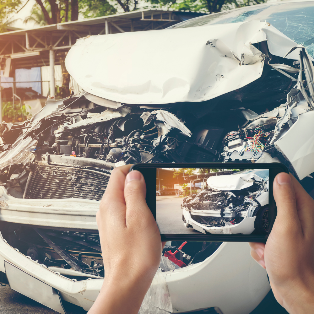 person taking a picture of a car which has been in an accident