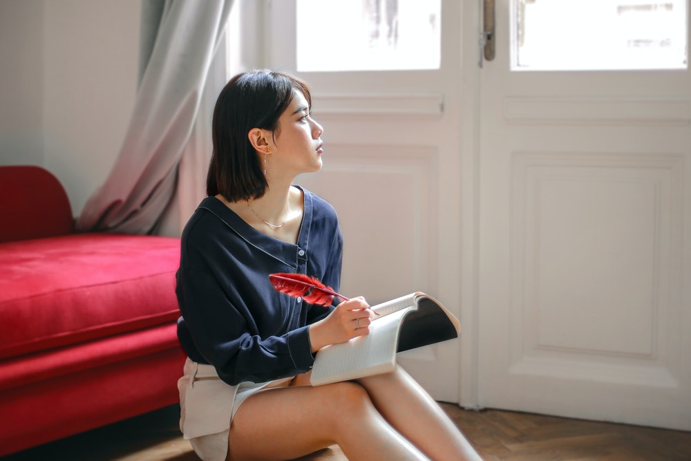 woman looking thoughtful and writing in a notebook