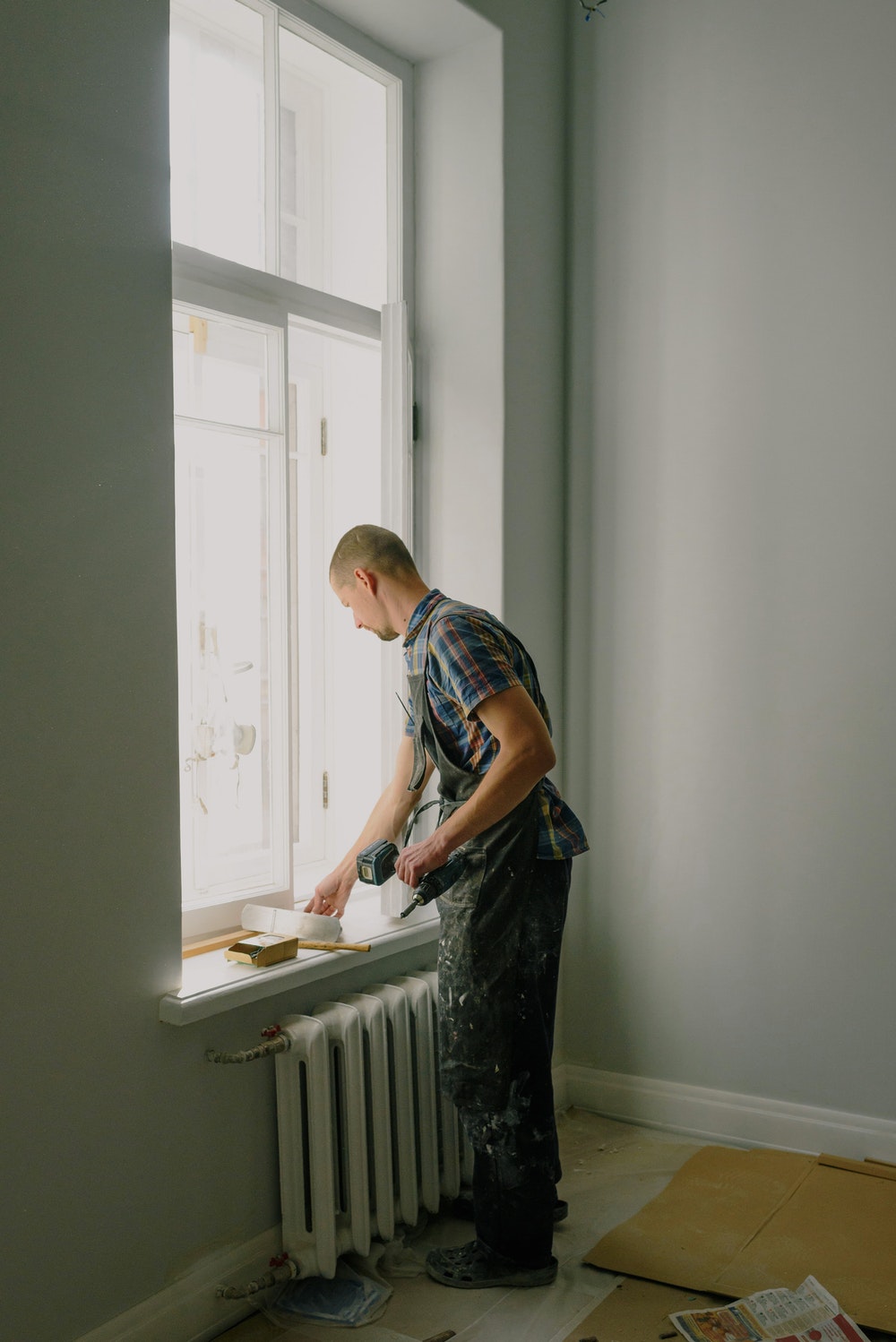 man stood by a window with tools preparing for a home renovation