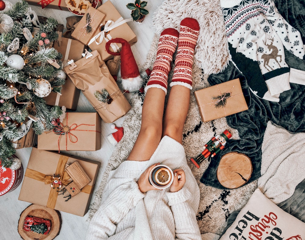 Woman sat near a Christmas tree holding a mug of tea