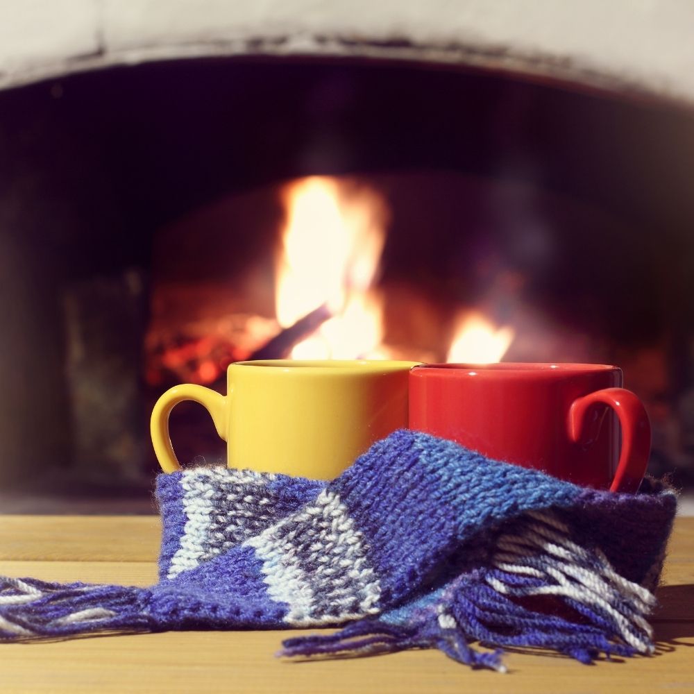 red and yellow cups wrapped in a blue scarf in front of a fire