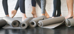people wearing leggings in front of rolled up mats