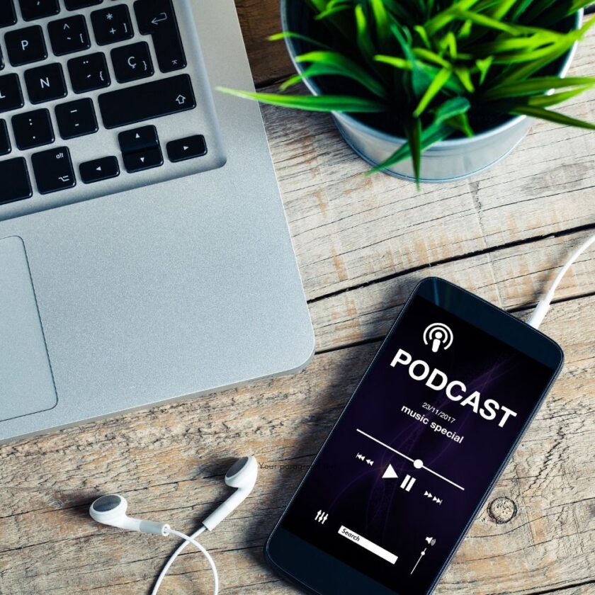 mobile phone with a podcast on it next to a laptop