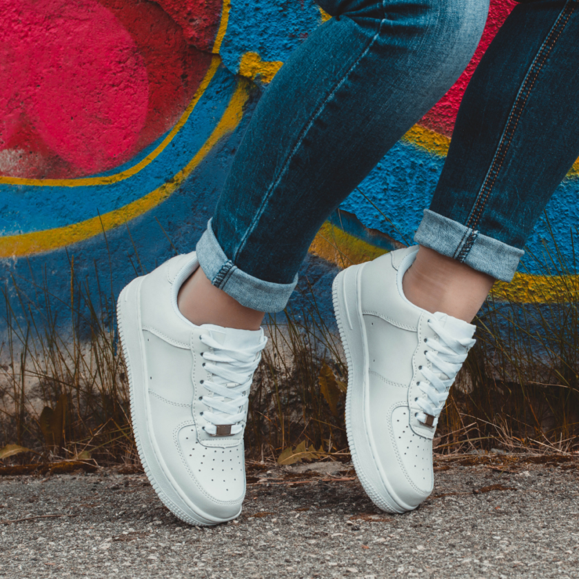 person wearing white sneakers with a graffiti background
