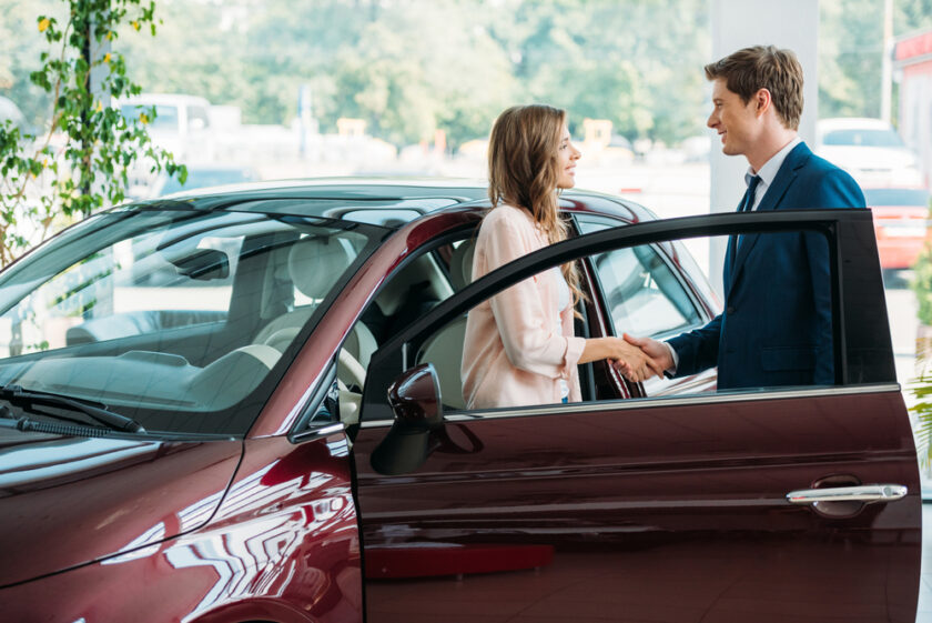 Women and man stood in a car sales room talking