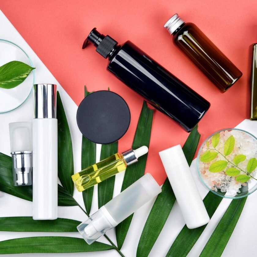 selection of cosmetic bottles sat on green leaves and a red backdrop