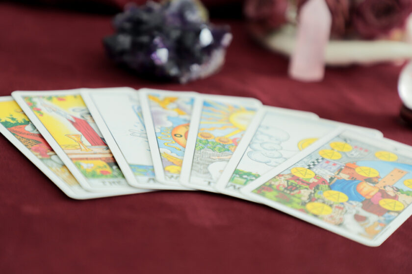 Selection of tarot cards on a red table setting with a cluster of crystals.