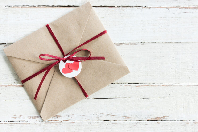 Gift wrapped up with a red bow and with a circular tag with two red hearts on it.