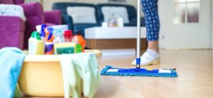 person cleaning a house with a mop and a bucket of cleaning products