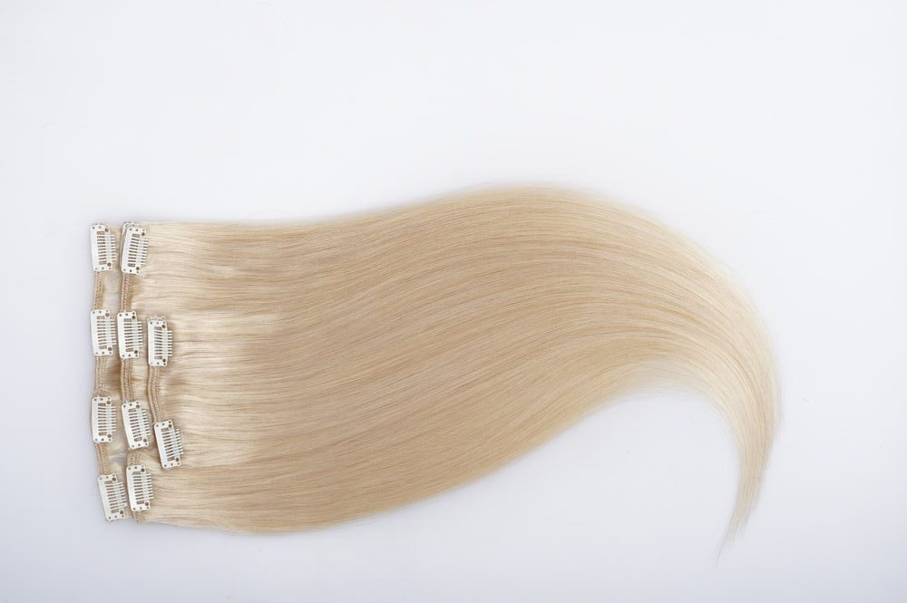 Straight blond remy virgin human hair clip in extensions on light grey background