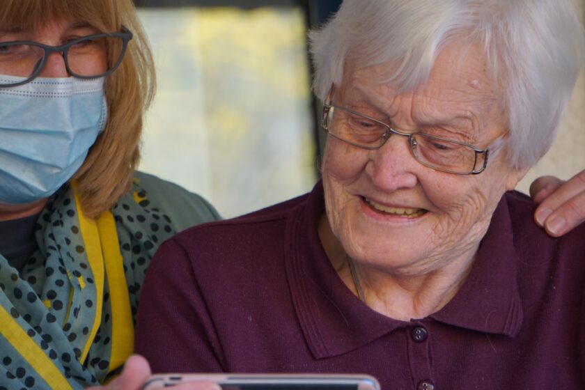 women in purple with a carer wearing a facemask behind them