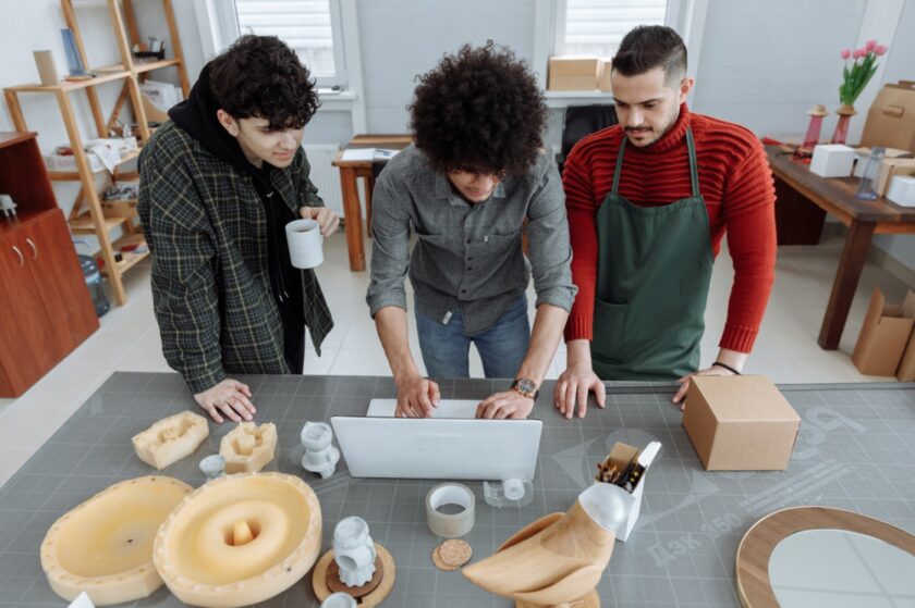 three people at work standing over a table