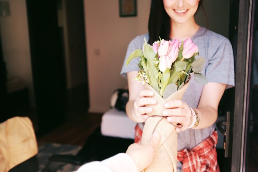 woman stood in a doorway holding a bunch of flowers