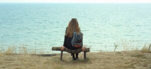 a young woman sat on a beach in front of the sea solo travelling