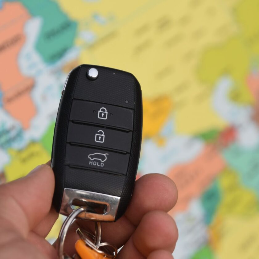 car keys being held in front of a map of the world