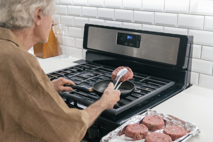 older gentleman frying beef on a grill