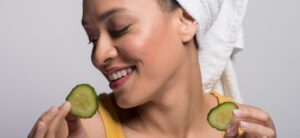 woman holding two slices of cucumber
