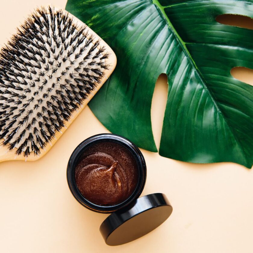 green haircare concept with hair brush leaf and glass tub with product in