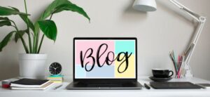 laptop sat on a desk with a colourful image saying blog