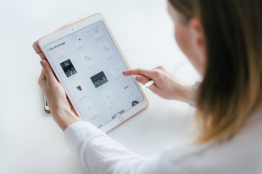 Image of a woman sat by a white table on an ipad