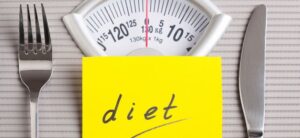 the word diet on scales with a knife and fork