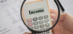 Person looking at a calculator with a magnifying glass which says income on it
