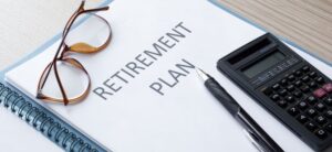 retirement plan written in a book with glasses and a calculate by it i