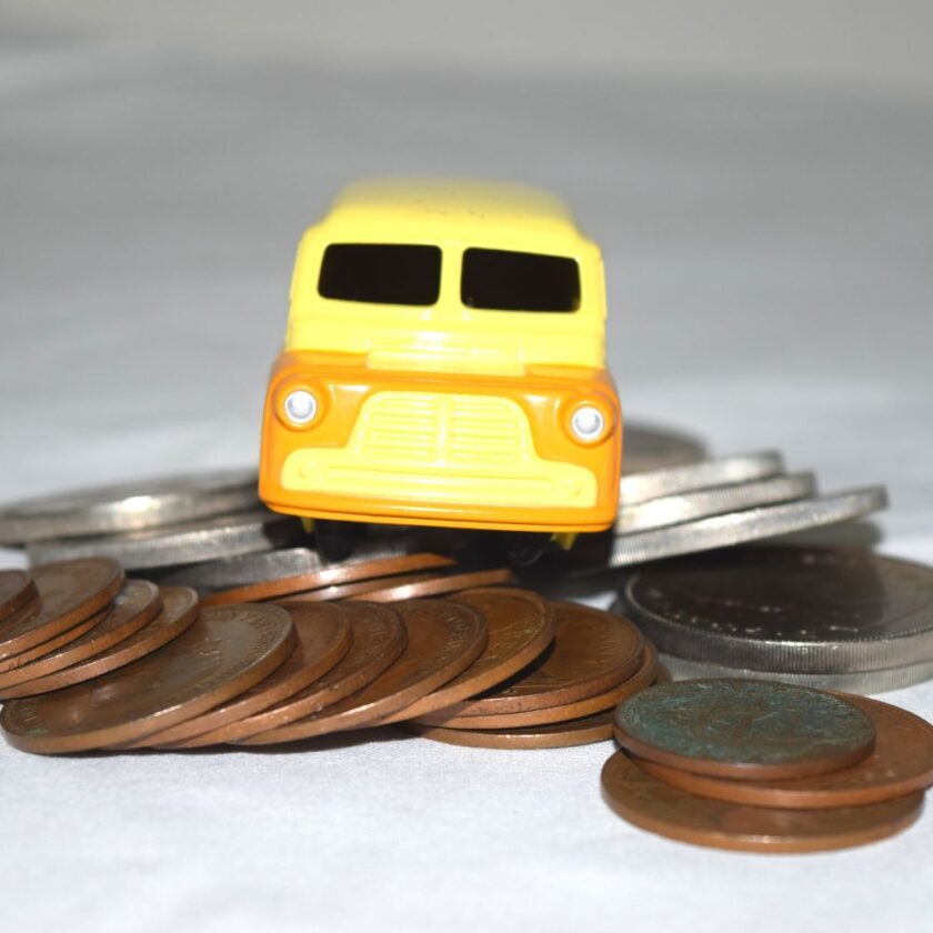 small yellow toy car sat on coins
