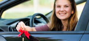 woman sat in a car holding a key with a ribbon round it