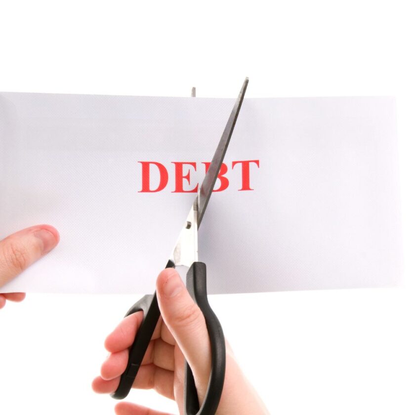 person cutting the word debt in half with scissors
