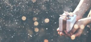 person holding a gift box in their hand with a sparkly backgound