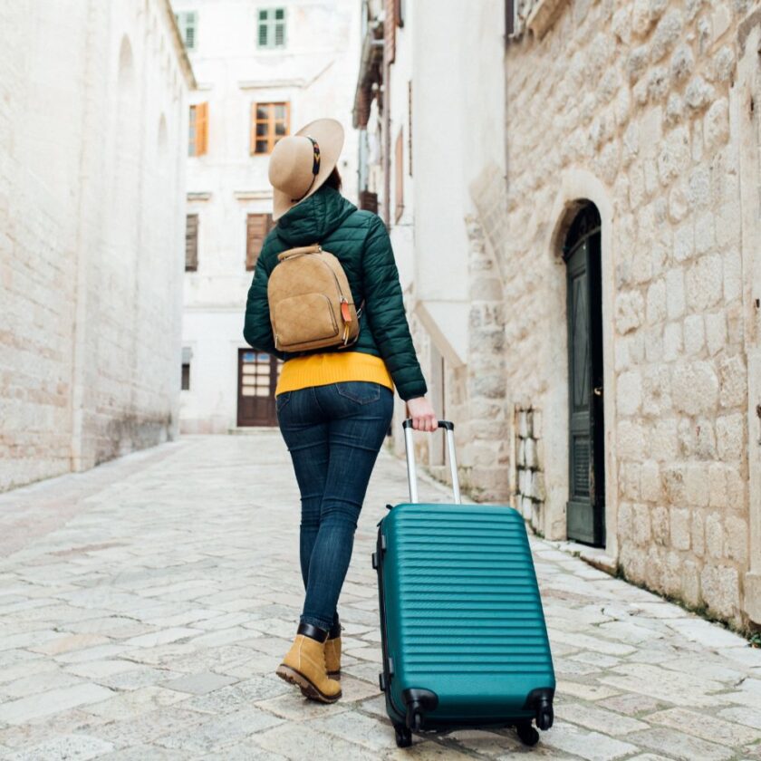 woman pulling luggage through an old town