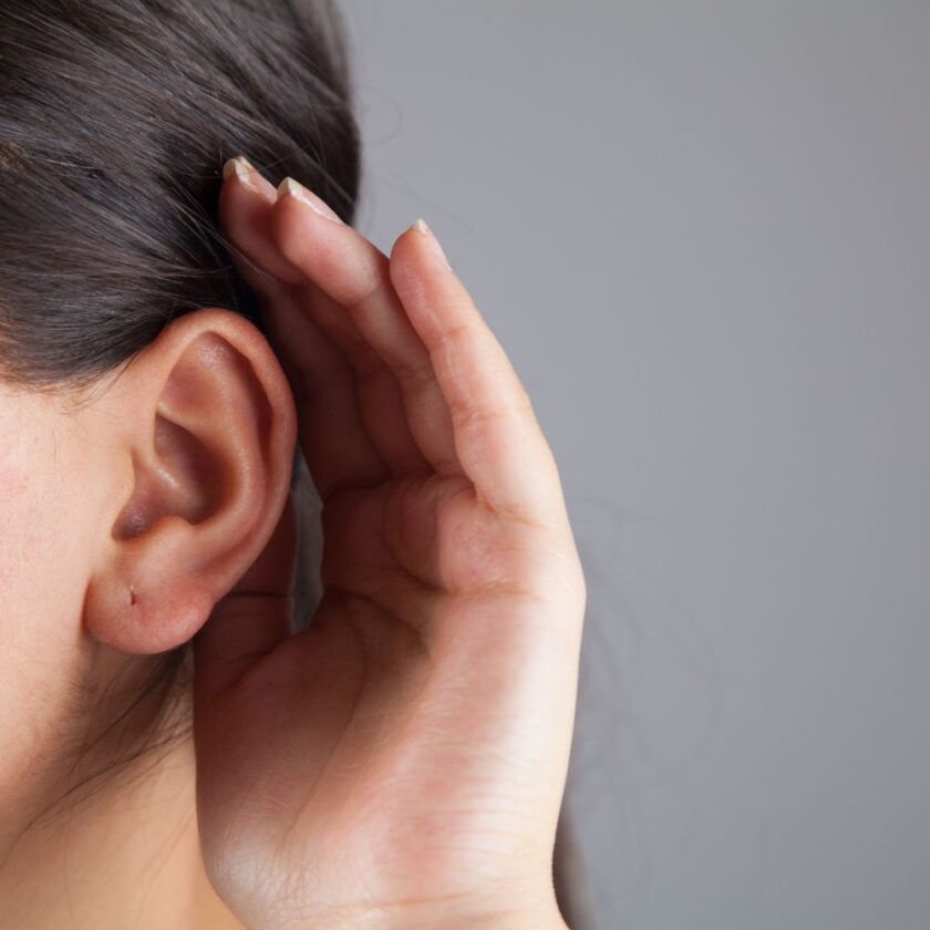 young woman with hand against their ear