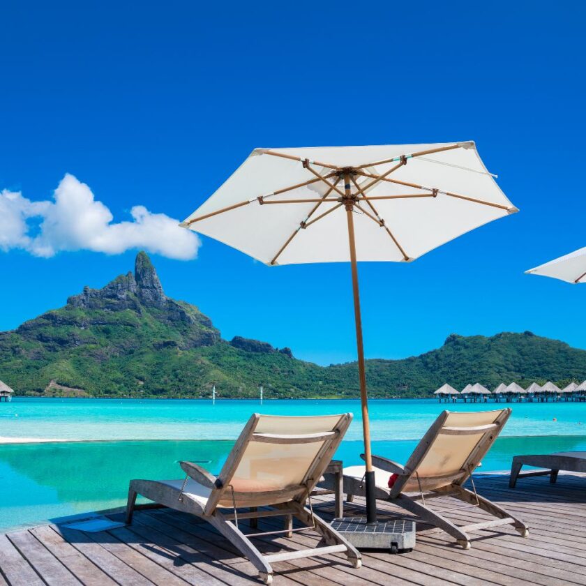 deck chairs and parasol near water with an island in the background
