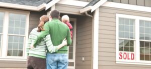 family stood outside a house with a sold sign in the window