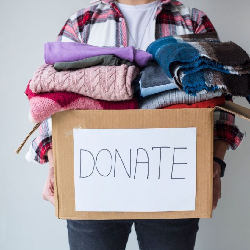 man holding a box of clothing with donate on it