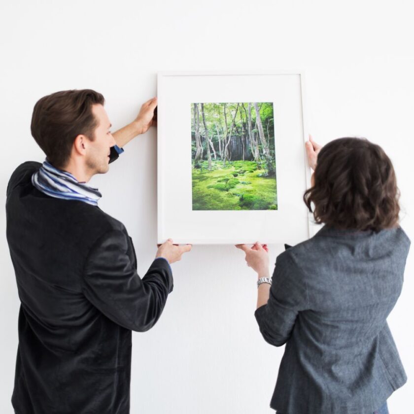 two people hanging a framed image on the wall