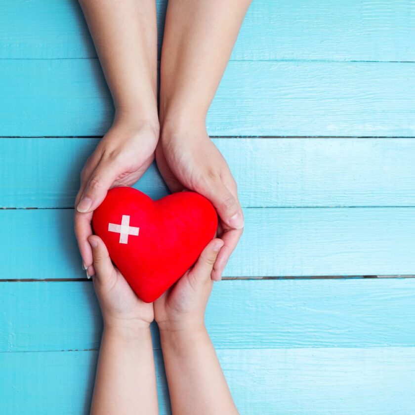 two people holding a heart with a white cross on it