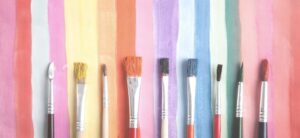 paint brushes on a colourful painted background