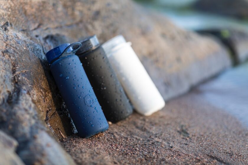 3 water drinking bottles leaning against a rock in blue black and white