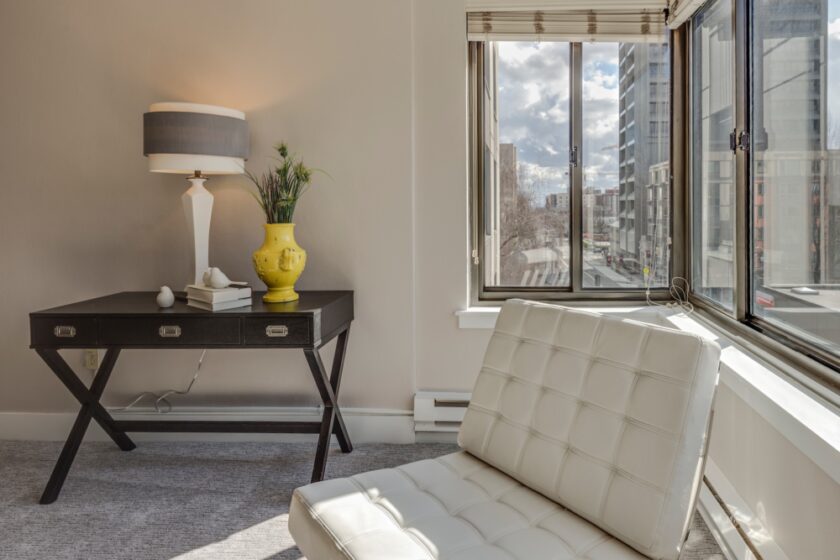 White table lamp and comfy chair by a window letting it light.