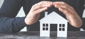 home security concept of a man holding his hands over a home